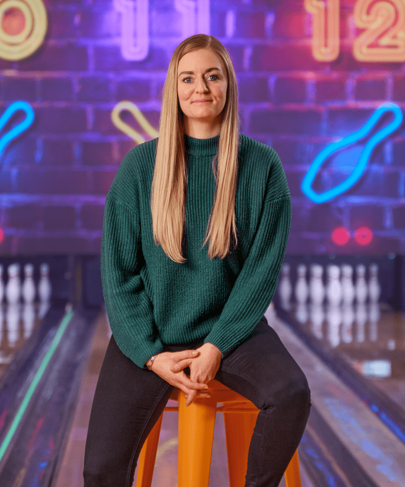 Kvinde i grøn sweater sidder på orange skammel